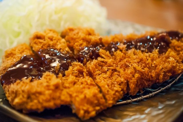 Tonkatsu mit Suace auf einem Teller serviert