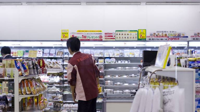 Ein Mitarbeiter in einem Seven Eleven in Japan von hinten vor den Regalen