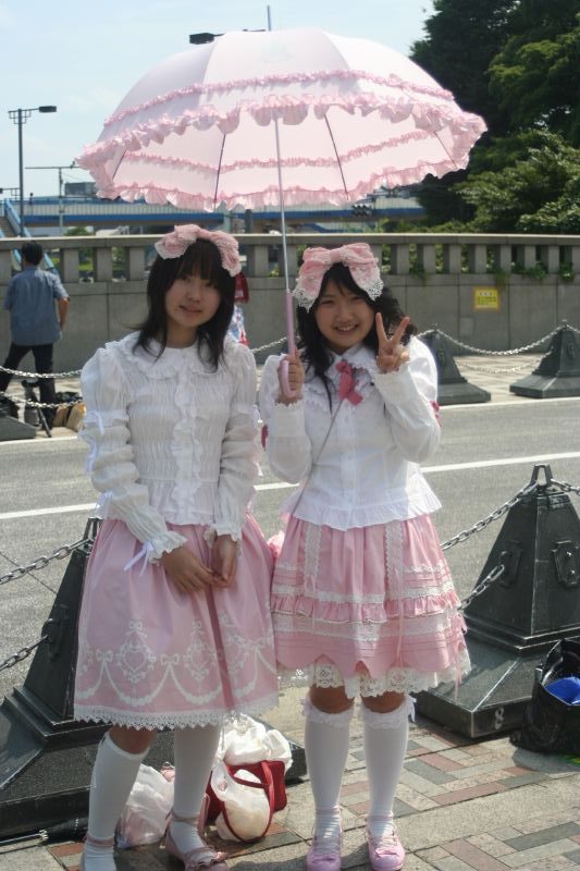 zwei japanische Frauen mit Sonnenschirm im rosa Lolita-Look posieren für ein Foto