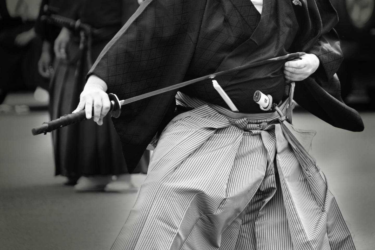 Ein in japanischem Gewand gekleideter Mann zieht ein Katana aus der Scheide