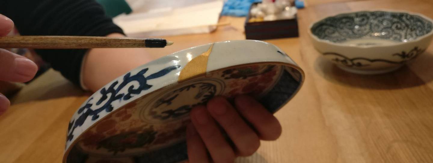 Ein gesprungener Teller wird mit Goldlack repariert.