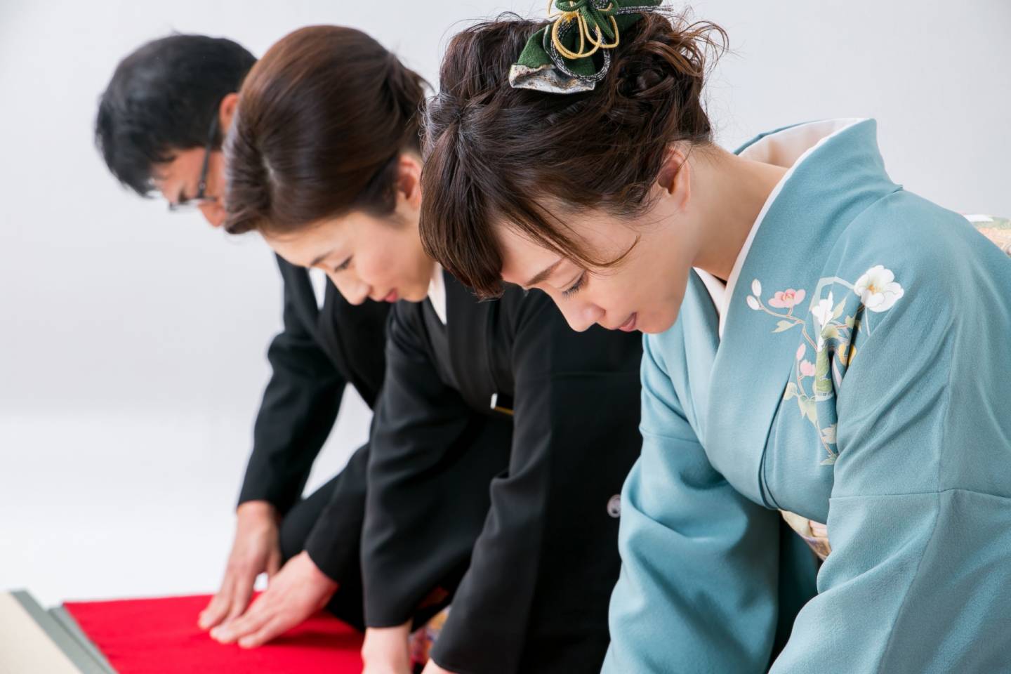 drei JapanerInnen verbeugen sich