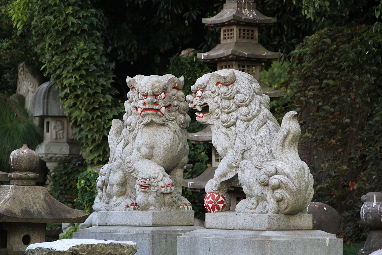 zwei steinerne Komainu vor Bäumen