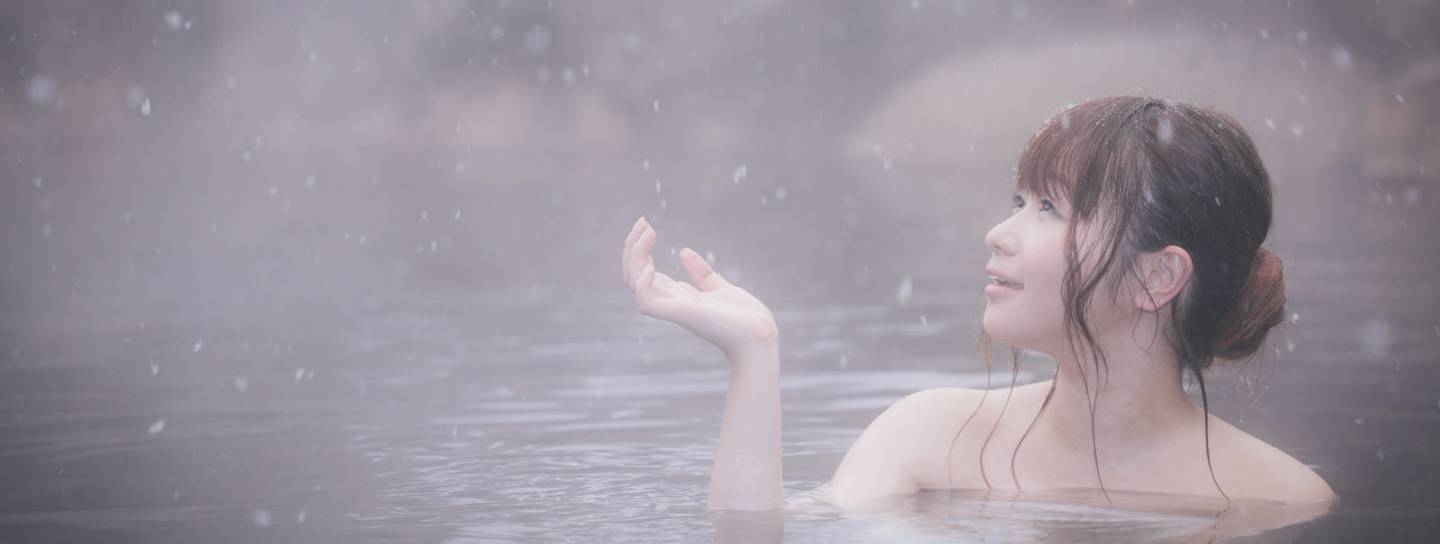 Bei Schnee im Onsen entspannende Frau