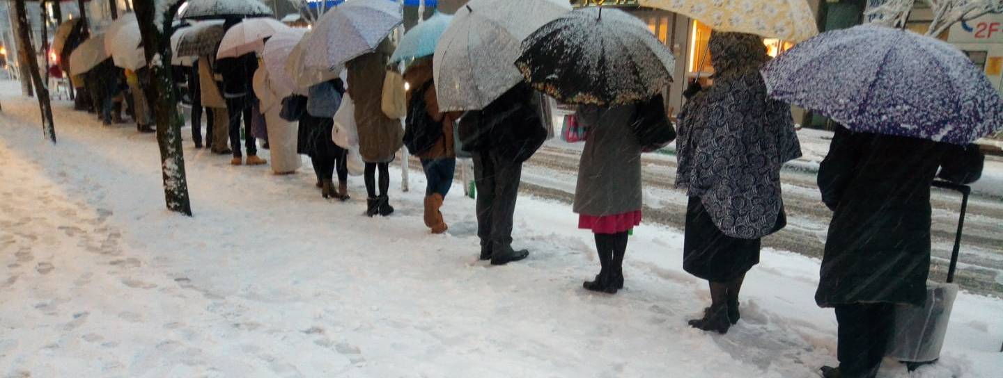 Japaner, die im Schnee Schlange stehen.