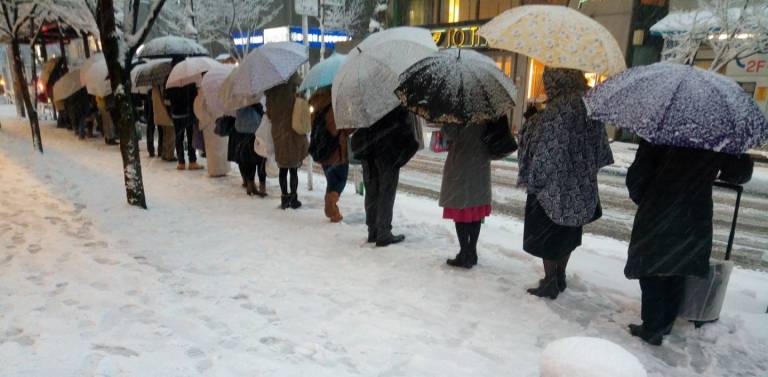 Japaner, die im Schnee Schlange stehen.
