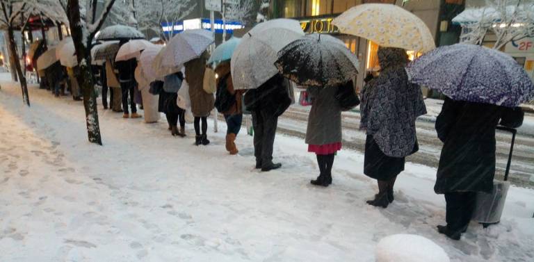 Japaner, die im Schnee Schlange stehen.