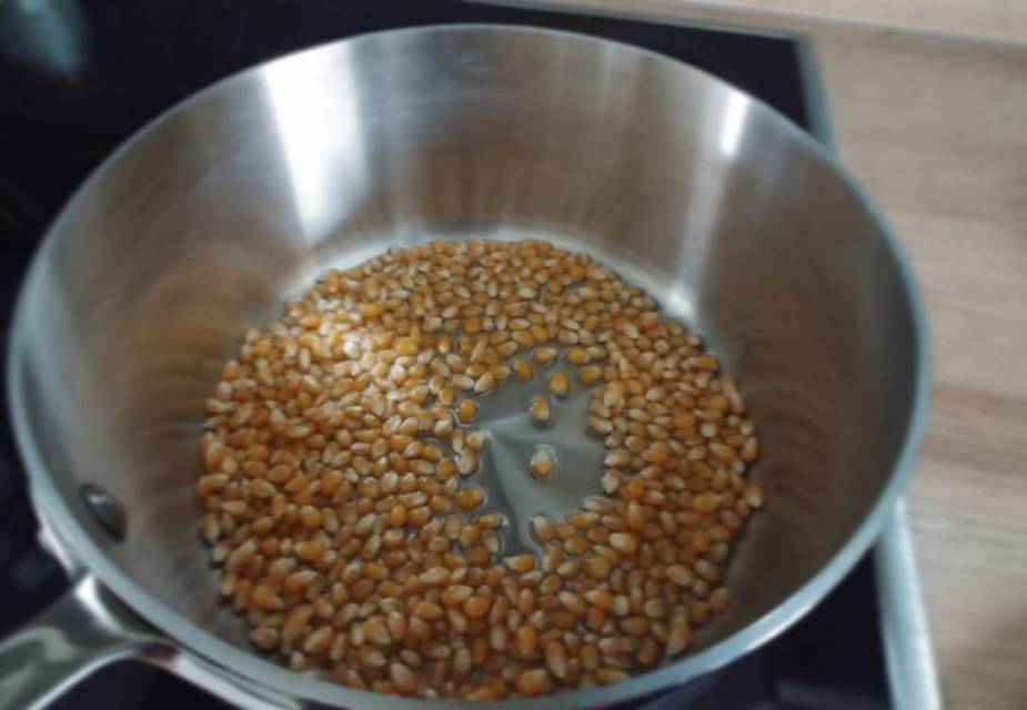 Mais in der Pfanne zu Popcorn aufplatzen lassen.