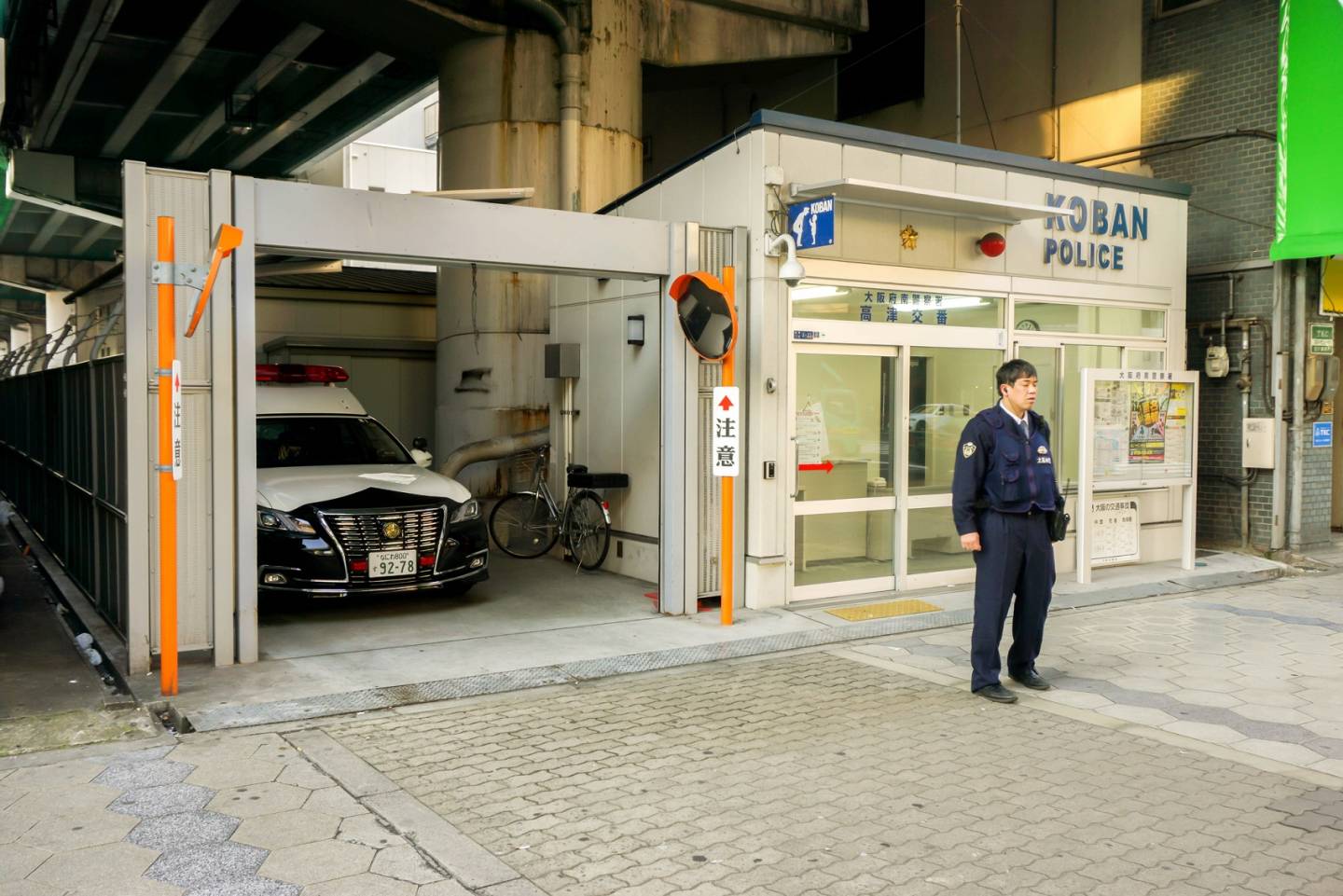 Ein Beamter beobachtet vor der Polizeibox die Umgebung.