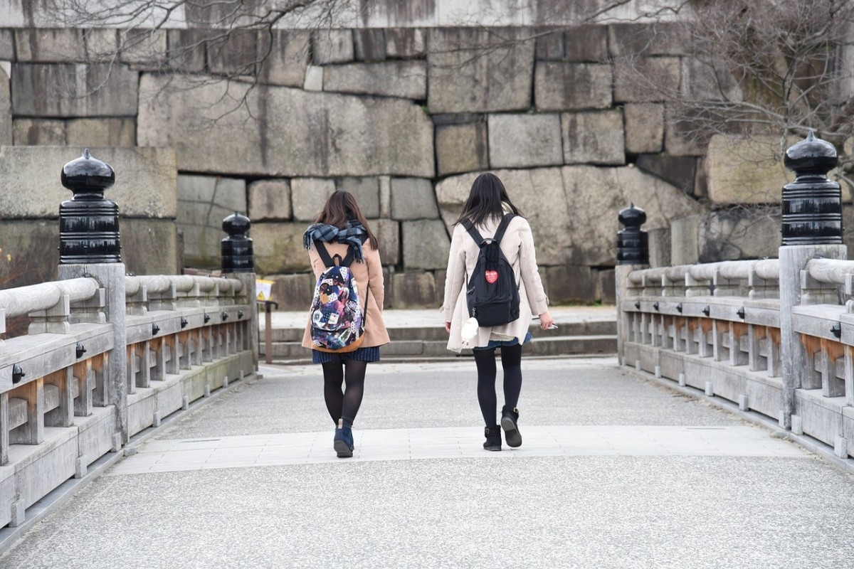 Zwei Frauen von hinten gehen auf eine japanische Burg zu