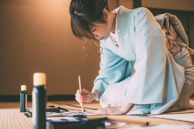 Frau im Kimono beim Kalligrafieren