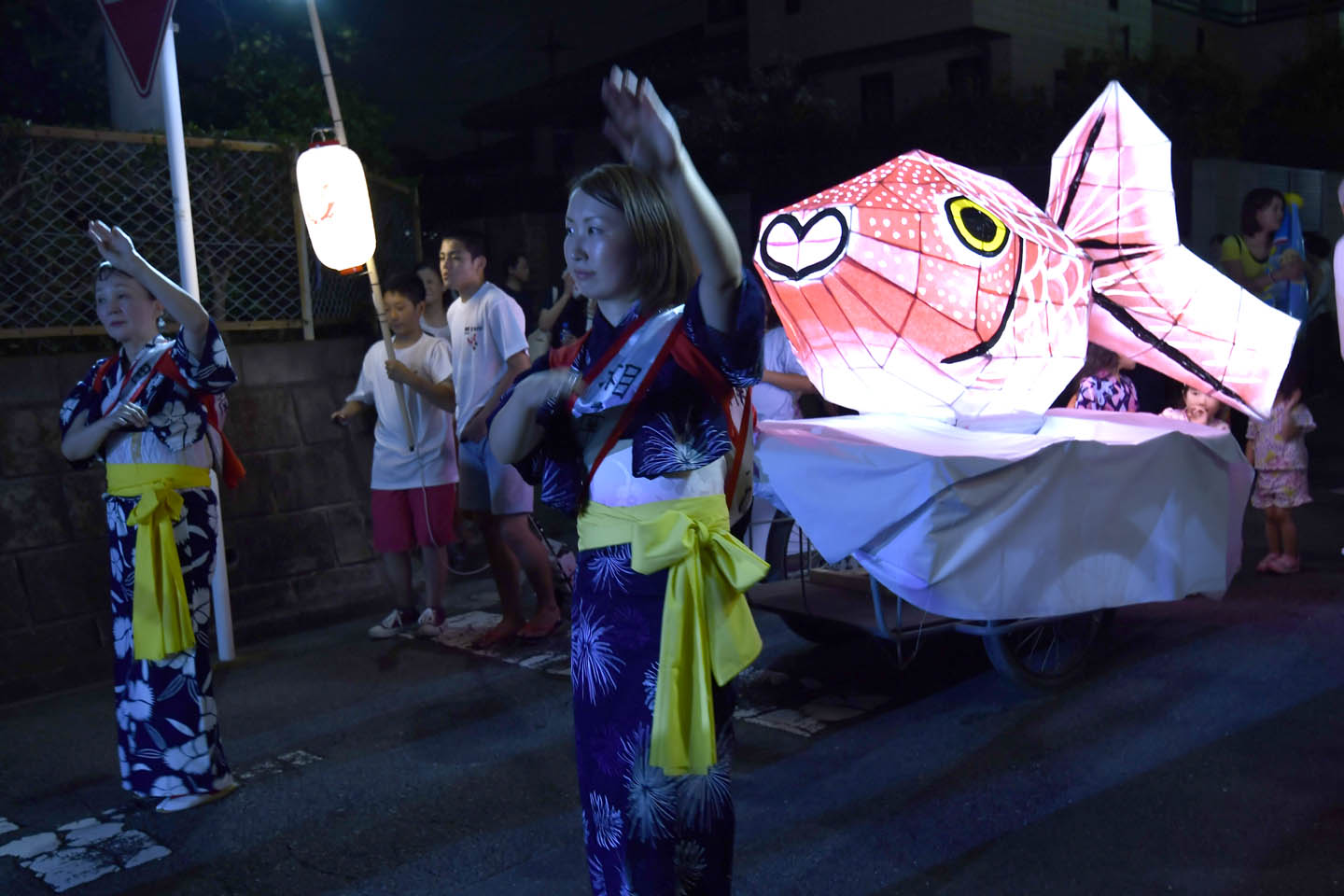 Frauen in Yukata bei einer Schreinparade mit beleuchteten Figuren
