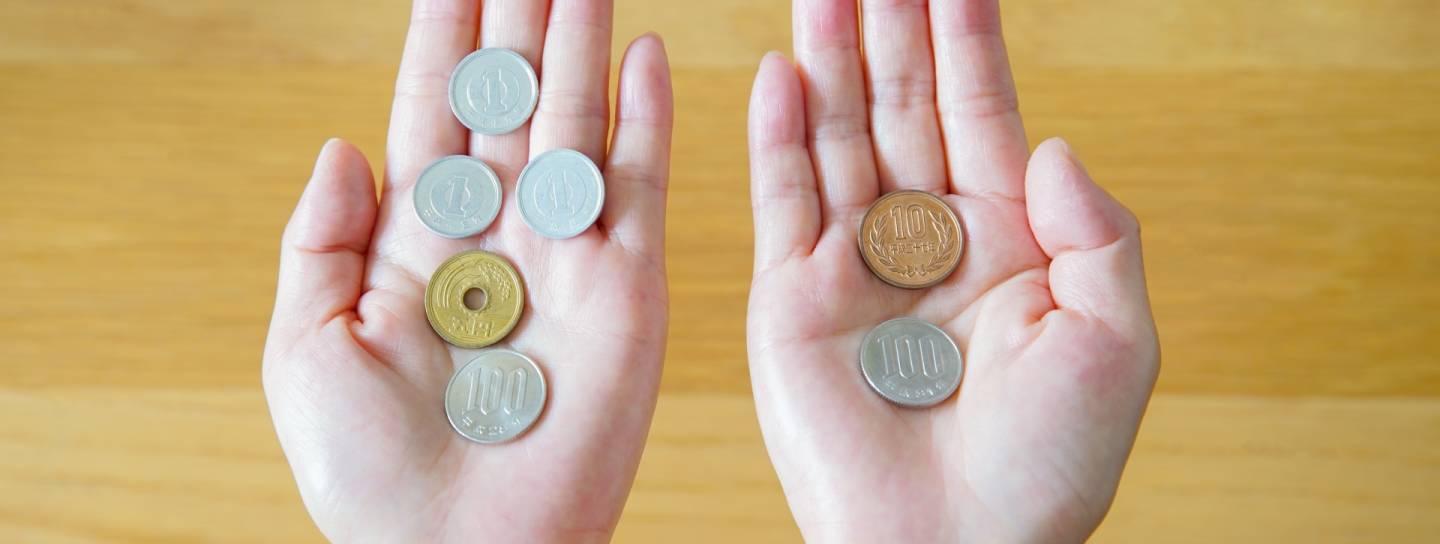 Zwei offene Hände halten Yen-Münzen