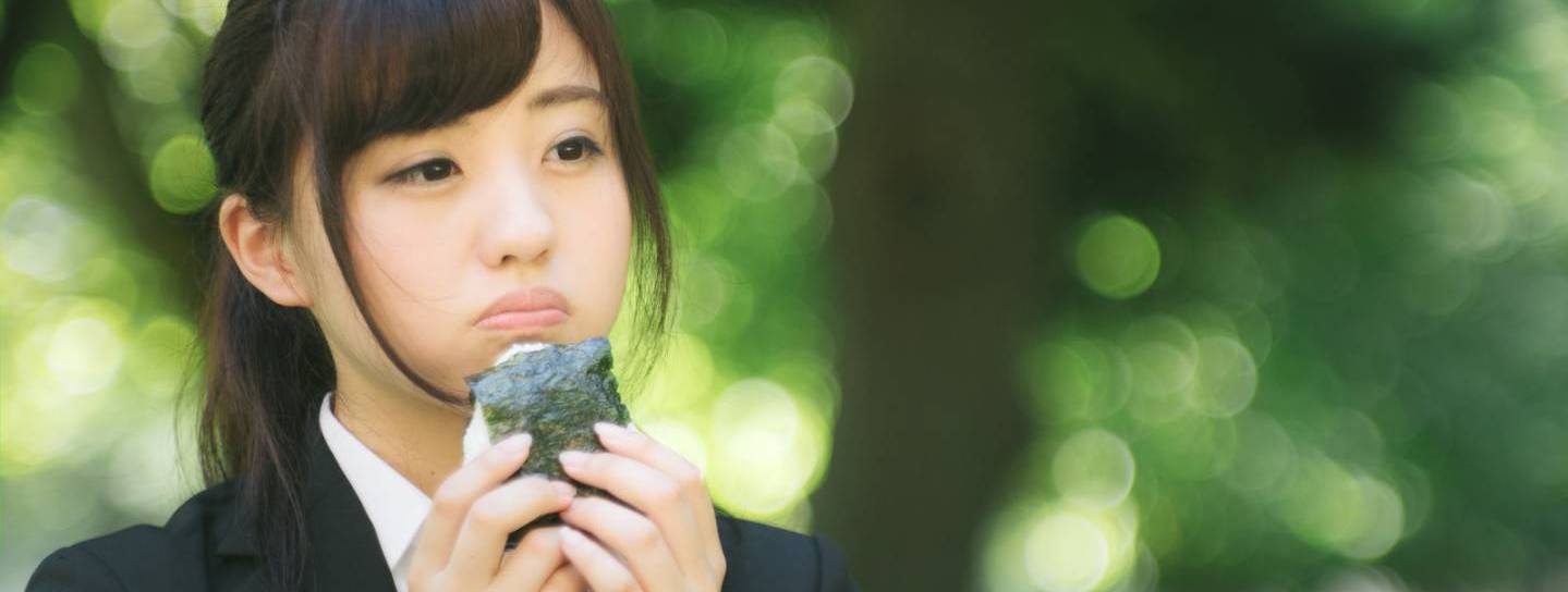 Eine Frau isst Onigiri im Park.