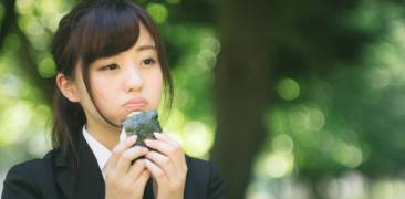 Eine Frau isst Onigiri im Park.