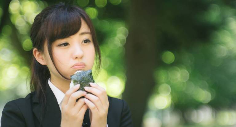 Eine Frau isst Onigiri im Park.