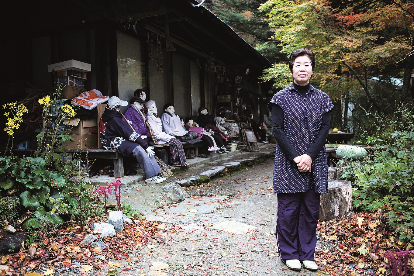 Puppenmacherin Tsukimi Ayano aus dem Dorf Nagoro vor ihrem Haus mit Puppen im Hintergrund