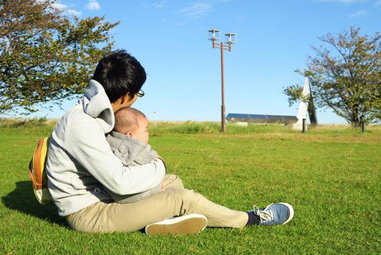 Vater auf einer Wiese mit Baby im Arm