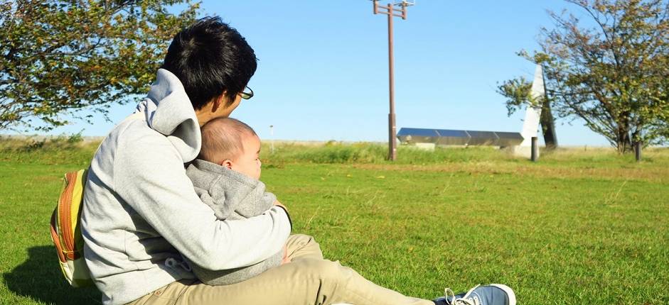 Vater auf einer Wiese mit Baby im Arm