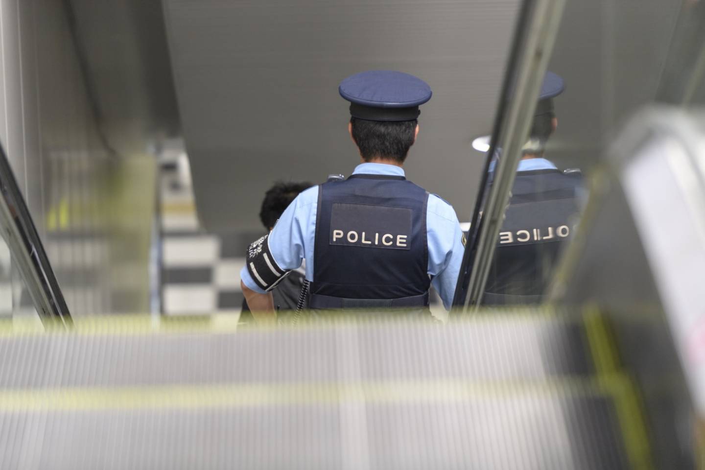 Japanischer Polizist auf einer Bahnhofs-Rolltreppe