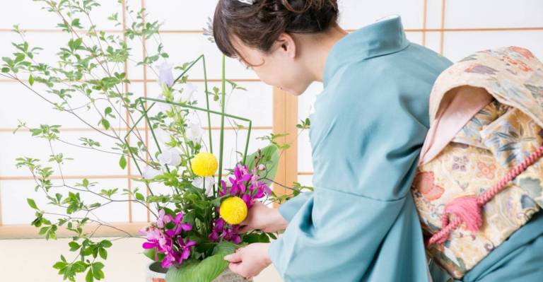 Frau im Kimono arrangiert Ikebana