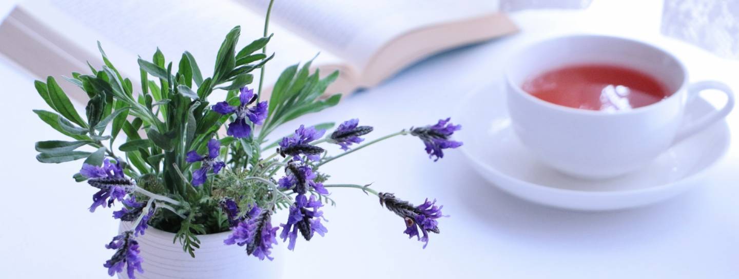 Blumenstrauß, Tee und aufgeschlagenes Buch
