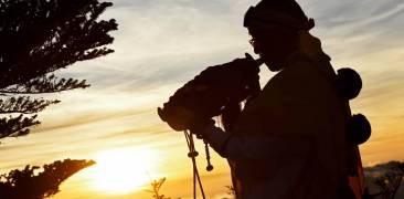 Ein Shugenja bläst ein Muschelhorn im Sonnenaufgang