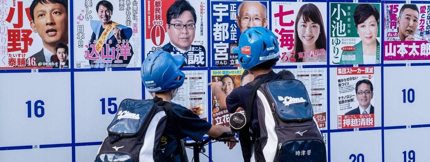 05. Juli 2020: Teenager schauen auf Wahlplakete verschiedener Kandidaten in Tokyo.