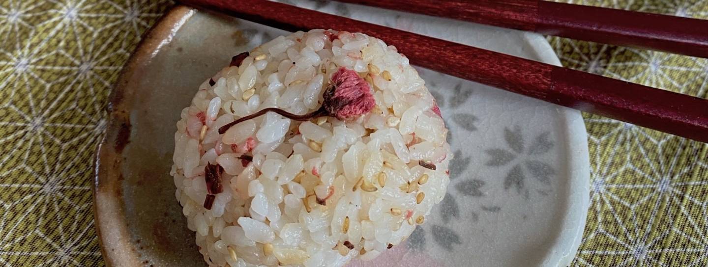 Reisbällchen mit Kirschblüten auf Tellereben mit Essstäbchen