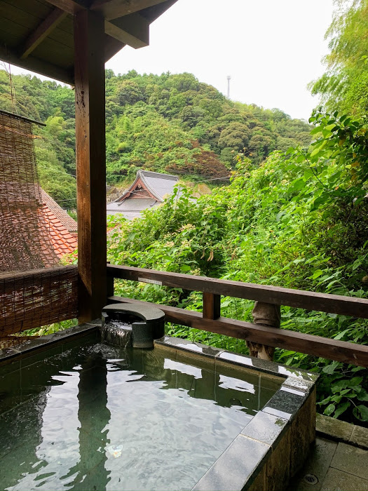 Morgenbad in Yunotsu, grüne Bäume im Hintergrund, die sich im klaren Wasser des rechteckigen Beckens spiegeln