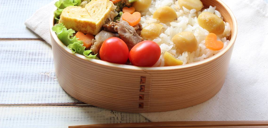 Bento-Box mit Rührei in Herzform, Salat, Tomaten und Reis mit Kastanien