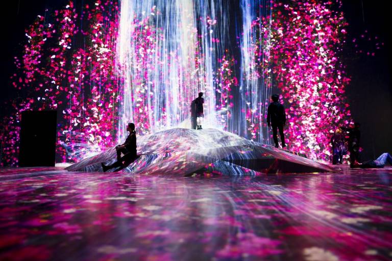 Ausstellung teamLab Borderless, pink-blaue Lichtinstallation mit staunenden Besuchern