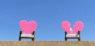 Zwei rosa Herzen in Sesseln vor blauem Himmel