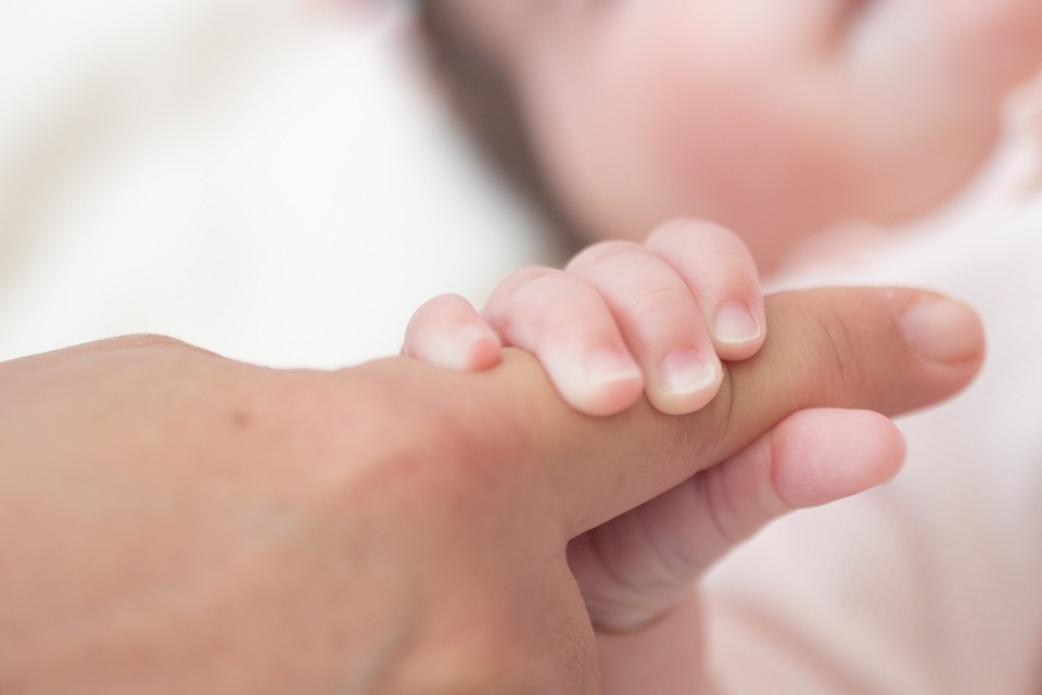 Ein Baby greift nach der Hand seiner Mutter