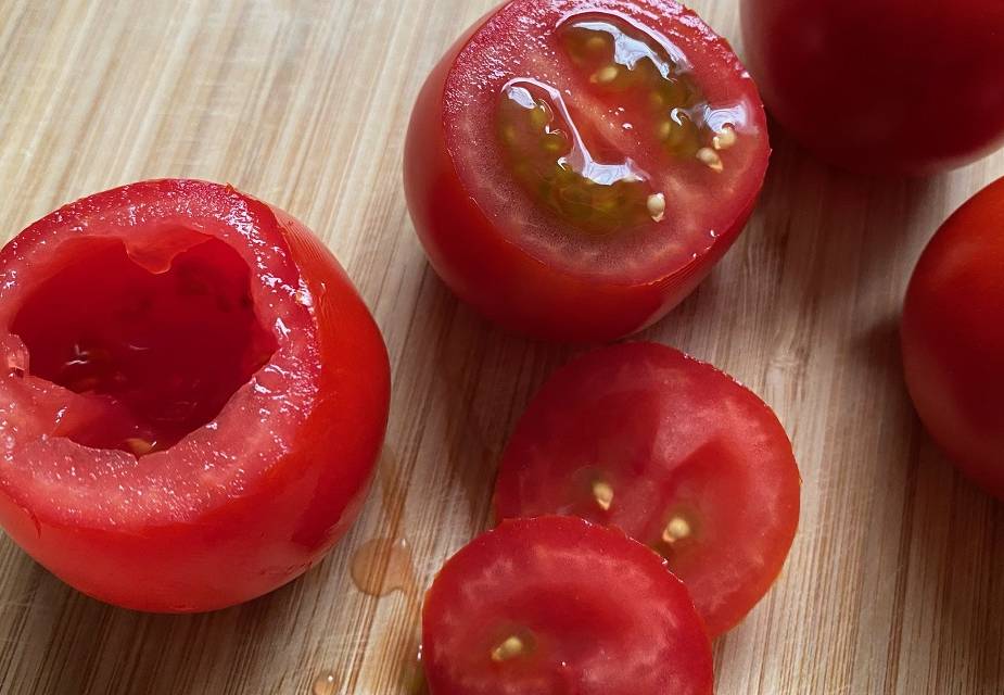 Halbe und ganze Cocktailtomaten auf Holzbrett