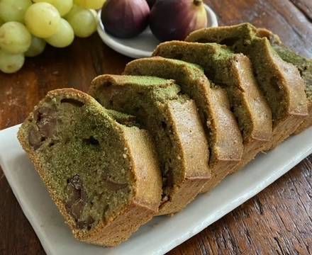 Matcha-Kuchen auf Teller angerichtet mit Weintrauben und Feigen im Hintergrund