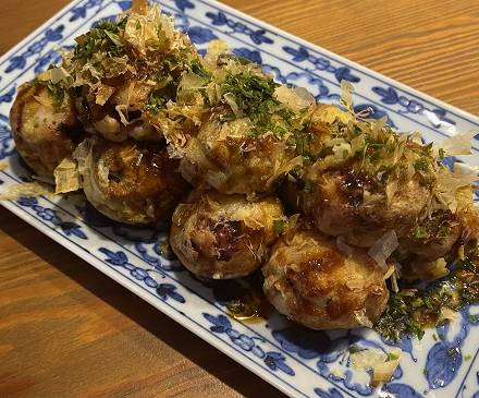 Takoyaki serviert auf blaugemusterter Platte