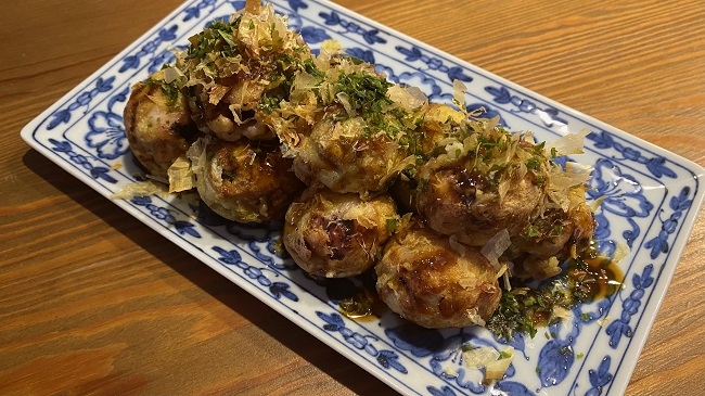 Takoyaki serviert auf blaugemusterter Platte