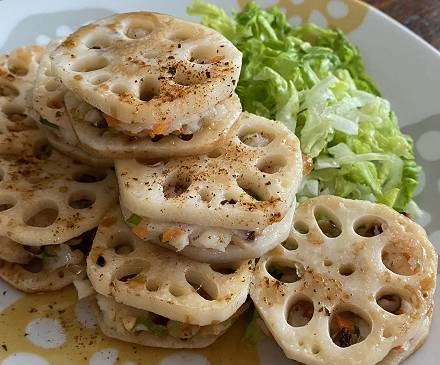 Lotoswurzel mit Gemüse und Kabeljau auf Teller mit grünem Salat angerichtet