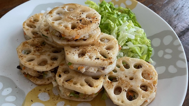 Lotoswurzel mit Gemüse und Kabeljau auf Teller mit grünem Salat angerichtet