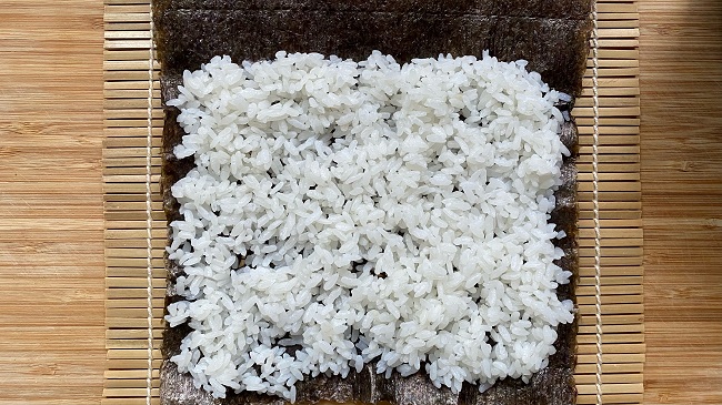 Sushi-Reis auf Nori-Blatt verteilen (am oberen Rand 3 cm. freilassen)