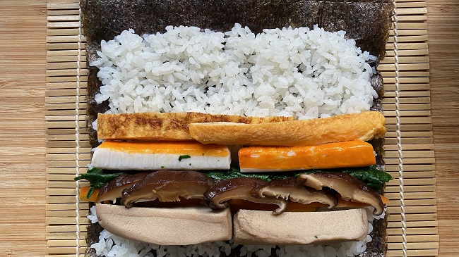 Sushi-Füllung wird auf dem Reis platziert