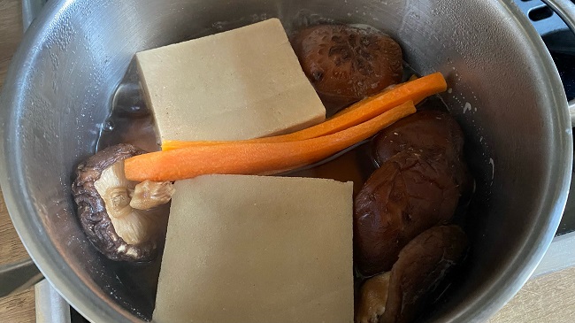 Shiitake, Tofu und Karotten mit Zucker, Mirin und Sojasauce in lauwarmem Wasser und Dashi kochen
