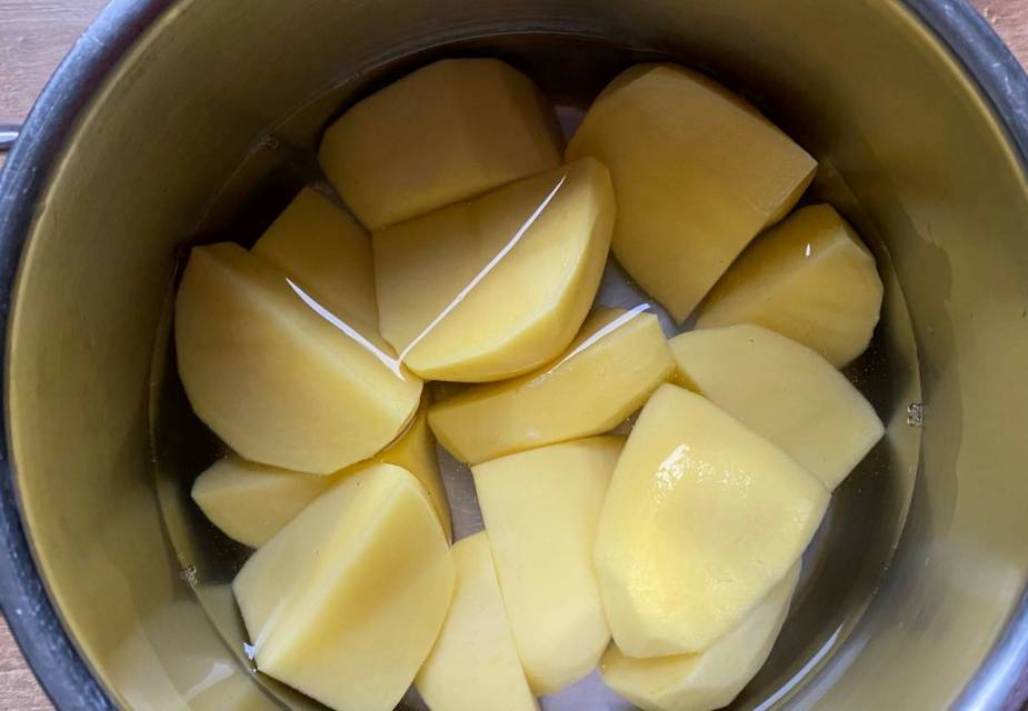 In gleich große Stücke geschnittene, geschälte Kartoffeln im Topf