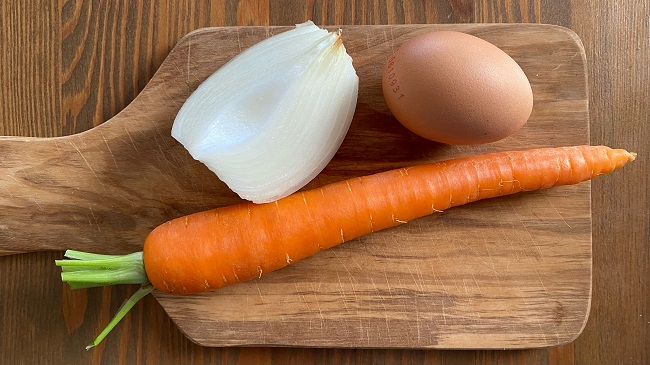 Zutaten für Kakiage auf einem Holzschneidebrett: Zwiebel, Karotte und Ei.