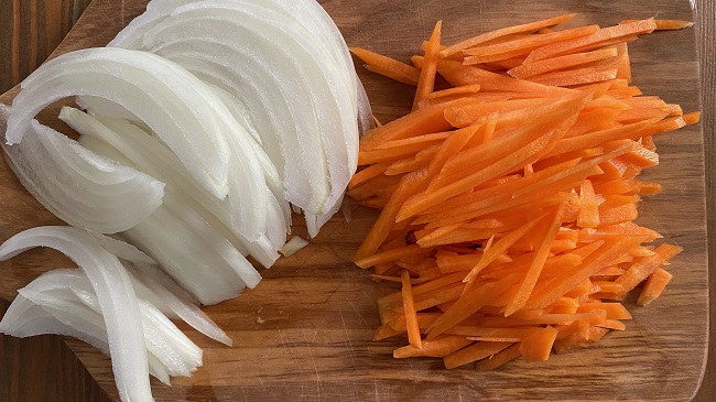 Karotte und Zwiebel in feine Streifen geschnitten auf Holzbrett