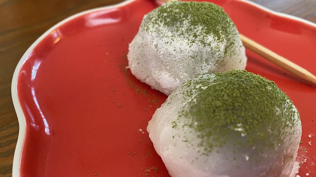 Fertige Mochi mit Matcha-Pulver bestreut auf rotem Teller serviert