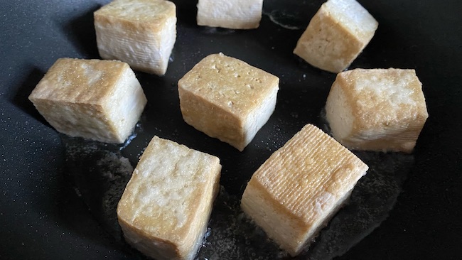 Tofu wird in der Pfanne goldbraun gebraten