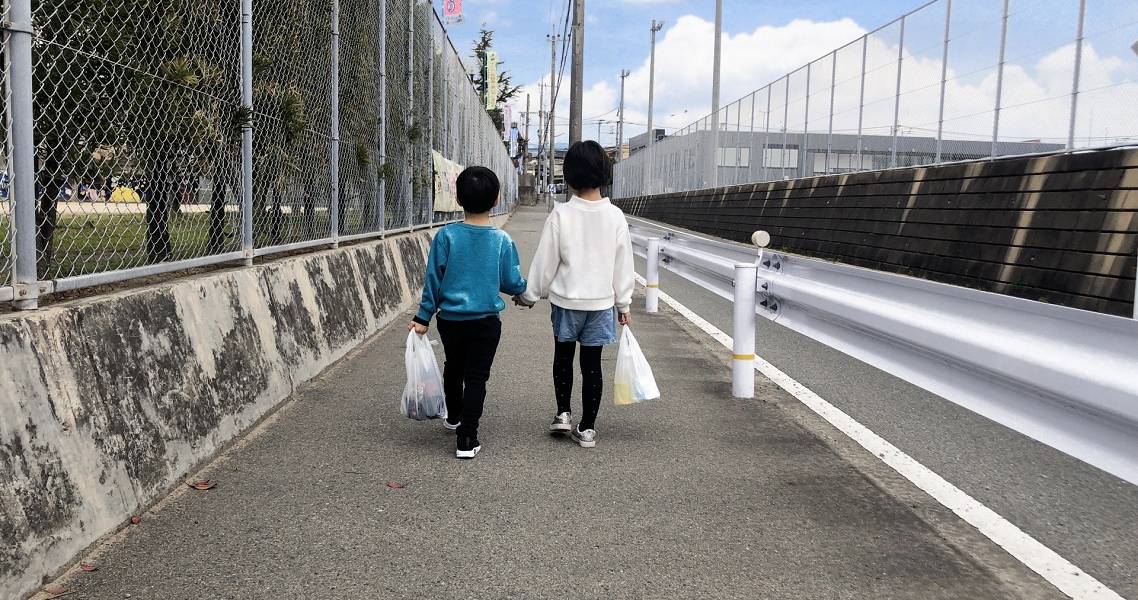 Zwei kleine Kinder gehen in Japan eine Straße entlang