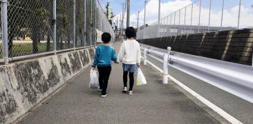 Zwei kleine Kinder gehen in Japan eine Straße entlang
